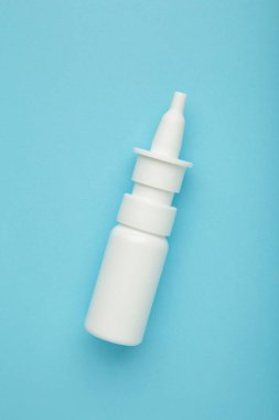 Mavi arka planda bir şişe burun damlası. Dikey fotoğraf. Üst görünüm