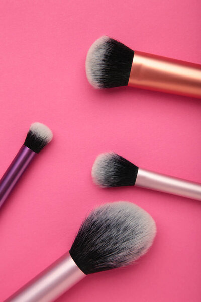Профессиональные женские косметические щетки для макияжа и щетки для ресниц на розовом фоне. Концепция косметики, составить концепцию. Вид сверху
