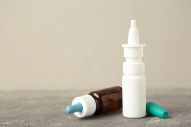 Gri arka planda bir şişe burun damlası. Mesaj için yer var. Üst görünüm