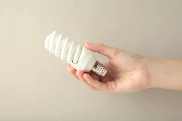 Light bulb in hand on grey background. Space for text. Top view