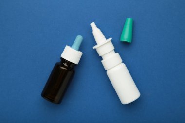 Mavi arka planda bir şişe burun damlası. Mesaj için yer var. Üst görünüm