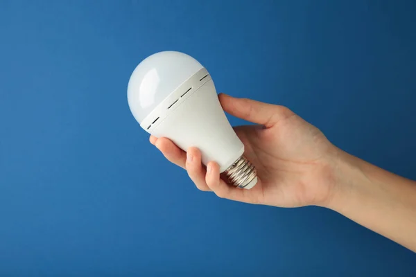 Light bulb in hand on blue background. Space for text. Top view