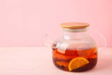 Pembe arka planda cam çaydanlıkta limonlu kırmızı çay. Sağlıklı içki konsepti. Üst görünüm