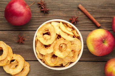 Tarçınlı kurutulmuş elma cipsi ve taze elmalı yıldız anason. Gri arkaplanda ev yapımı kurumuş organik elma dilimi. Üst görünüm
