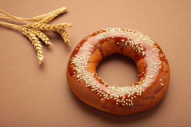 Fresh bread bagel with seed on brown background. Top view clipart