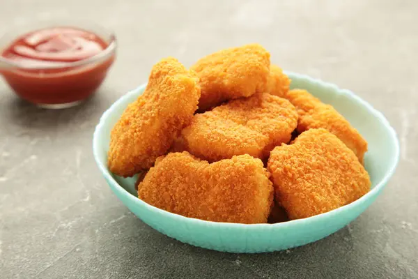 Chicken nuggets with ketchup on plate on grey background. Top view
