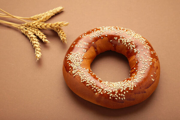 Свежий бублик с семенами на коричневом фоне. Вид сверху