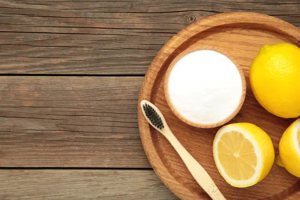 Limonlu beyaz diş fırçası ve gri ahşap arka planda kabartma tozu. Üst görünüm