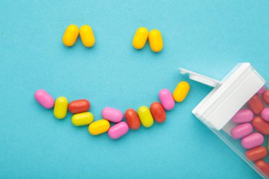 Renkli meyve şekerlemeleri mavi arka planda bir gülümseme şeklinde yatar. Üst görünüm