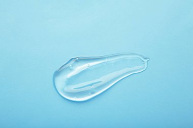 Pastel mavi bir arka planda kremalı makyaj malzemesi lekeleri. Üst görünüm