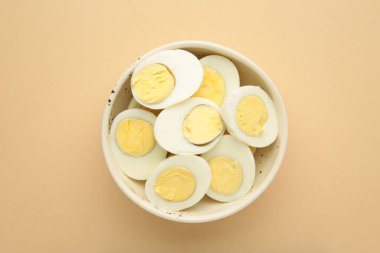 Bej arka planda bir kasede haşlanmış yumurta. Üst görünüm