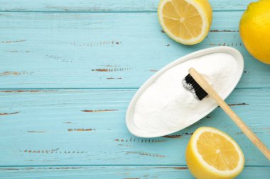 Mavi ahşap arka planda limonlu diş fırçası ve kabartma tozu. Mesaj için yer var. Üst görünüm