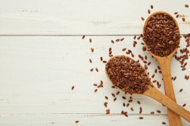 Beyaz arka planda tahta kaşıkta keten tohumu. Üst görünüm