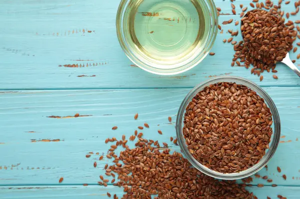 Mavi ahşap arka planda keten tohumu ve yağ şişesi