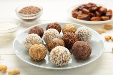 Sağlıklı ham enerji topları. Beyaz arka planda şeker vegan topları, fındık ve hindistan cevizi tabağı.