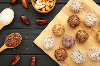 Sağlıklı ev yapımı enerji topları, kızılcık, fındık, hurma ve siyah arka planda kesilmiş yulaf. Üst görünüm