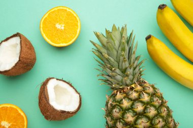 Tropik meyveler. Ananas, hindistan cevizi, nane arkaplanda portakal ve muz. Üst görünüm