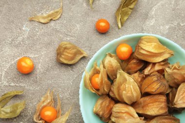 Physalis Peruviana meyvesi gri arka planda naneli bir plaka üzerinde. Üst görünüm