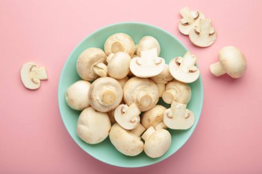 Pembe zemin üzerinde taze beyaz şampiyon mantarları. Üst görünüm