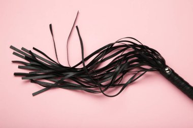 Deri bdsm pembe arka planda kırbaç. BDSM için erotik oyuncaklar. Üst görünüm