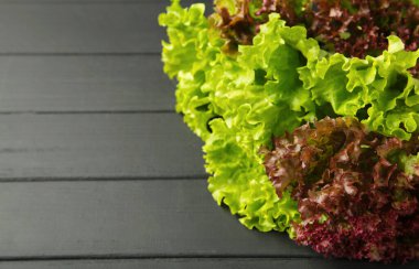 Siyah ahşap arka planda taze kırmızı ve yeşil marul. Üst görünüm