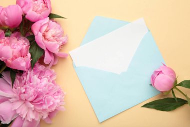 Pembe şakayık çiçekleri, zarf ve bej arka planda kağıt kart. Üst görünüm