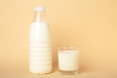 Bej arka planda bir bardak ve bir şişe süt. Metin için boşluk