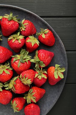 Siyah ahşap arka planda siyah tabakta taze çilek. Metin için boşluk