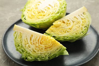 Gri arka planda koyu tabakta taze kesilmiş lahanalar. Üst görünüm