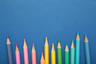 Mavi arka planda pastel renkli kalemler. Metin için boşluk