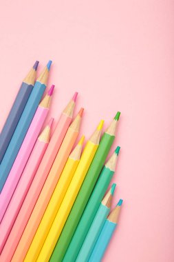 Pembe arka planda pastel renkli kalemler. Dikey fotoğraf. Üst görünüm