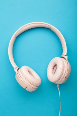 Mavi arka planda pembe kulaklıklar. Dikey fotoğraf. Üst görünüm