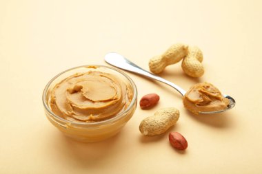 Bej arka planda bir kase fıstık ezmesi ve fıstık. Küçük kasede kremalı fıstıklı makarna. Üst görünüm