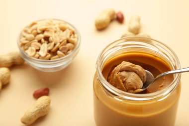 Bej arka planda kavanoz dolusu fıstık ezmesi. Üst görünüm