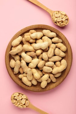 Taze sağlıklı fıstıklar kasede ve kaşık pembe arka planda. Üst Manzara. Süper Yiyecekler.