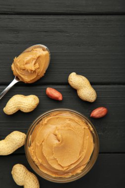 Siyah arka planda bir kase fıstık ezmesi ve fıstık. Küçük kasede kremalı fıstıklı makarna. Üst görünüm