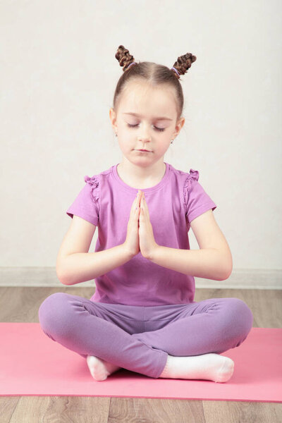 Очаровательная маленькая девочка улыбается во время занятий йогой. вид сверху