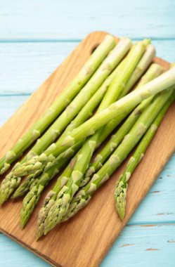 Mavi ahşap arka planda kesilmiş taze yeşil kuşkonmaz. Dikey fotoğraf