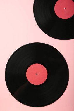 Pembe arka planda gramofon plakları var. Dikey fotoğraf. Üst görünüm