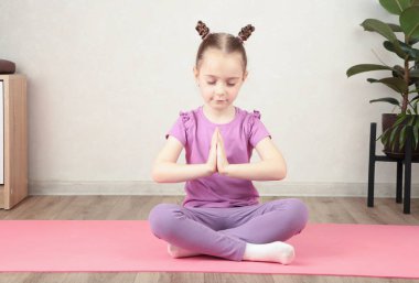 Sevimli küçük kız yoga yaparken gülümsüyor. en üstteki görünüm