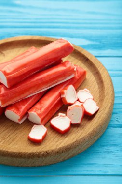 Mavi ahşap arka planda tahta tabakta yengeç çubukları. Üst görünüm