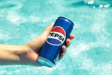 Mykolaiv, Ukrayna - Haziran 2024: Soğuk içecek Pepsi elinde havuzun zeminine karşı.