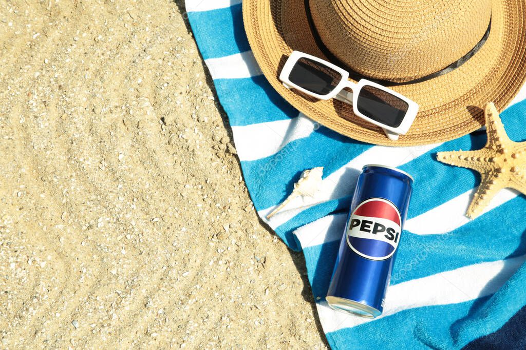 Mykolaiv, Ukraine - June 2024: Cold Pepsi can on the beach with towel, sunglasses and hat. PepsiCo.