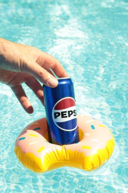 Mykolaiv, Ukrayna - Haziran 2024: Soğuk içecek Pepsi elinde havuzun zeminine karşı.
