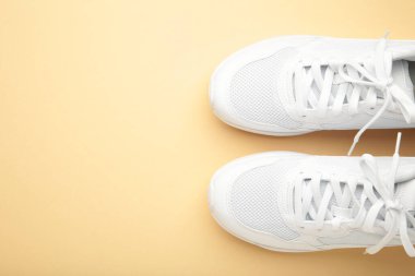 Bej arka planda beyaz spor ayakkabılar. Üst görünüm