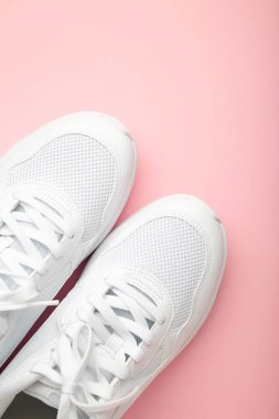 Pembe arka planda beyaz spor ayakkabılar. Dikey fotoğraf. Üst görünüm