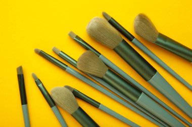 Sarı arka planda makyaj için fırça seti. Üst görünüm