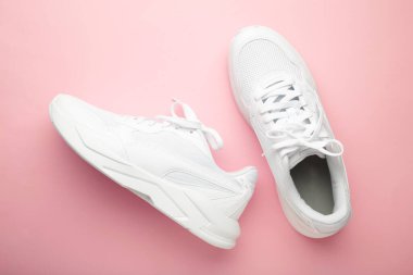 Pembe arka planda beyaz spor ayakkabılar. Üst görünüm