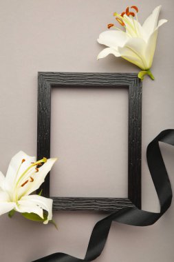 Boş çerçeveli güzel zambak çiçeği ve gri beton arka planda siyah cenaze kurdelesi..