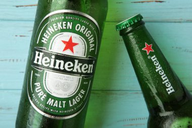 Mykolaiv, UKRAINE - Temmuz 2024: Mavi ahşap arka planda bir şişe Heineken Lager Birası.